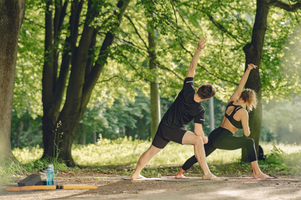 Pareja realizando ejercicios al aire libre en un parque, destacando los beneficios del entrenamiento para la salud física.