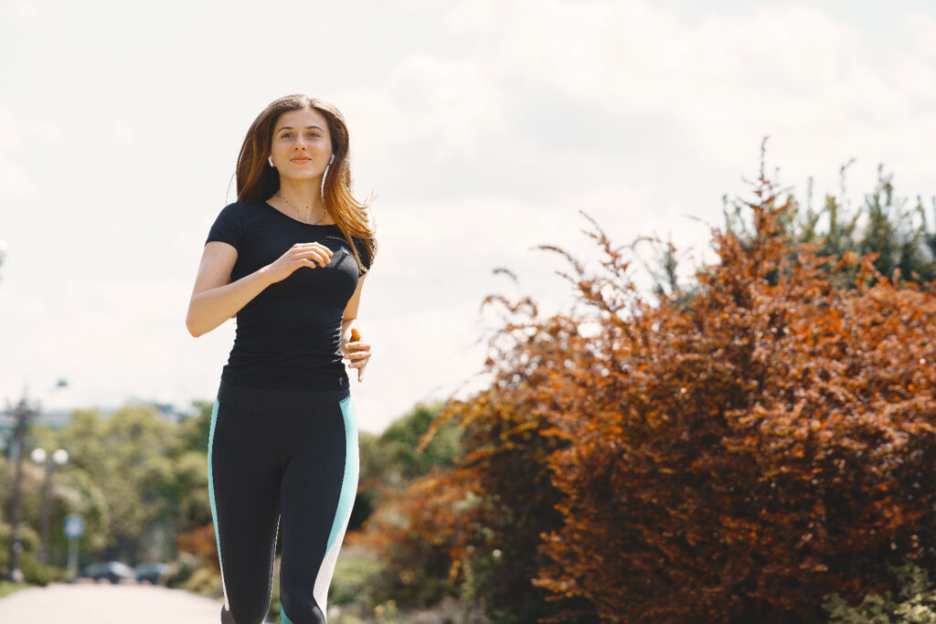 Mujer joven corriendo al aire libre en un día soleado, ideal para mantener una rutina de ejercicio saludable y activa.